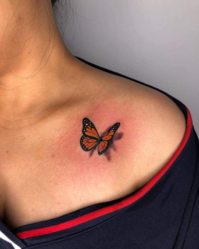 A monarch butterfly tattoo, vibrant and detailed, graces a person's shoulder