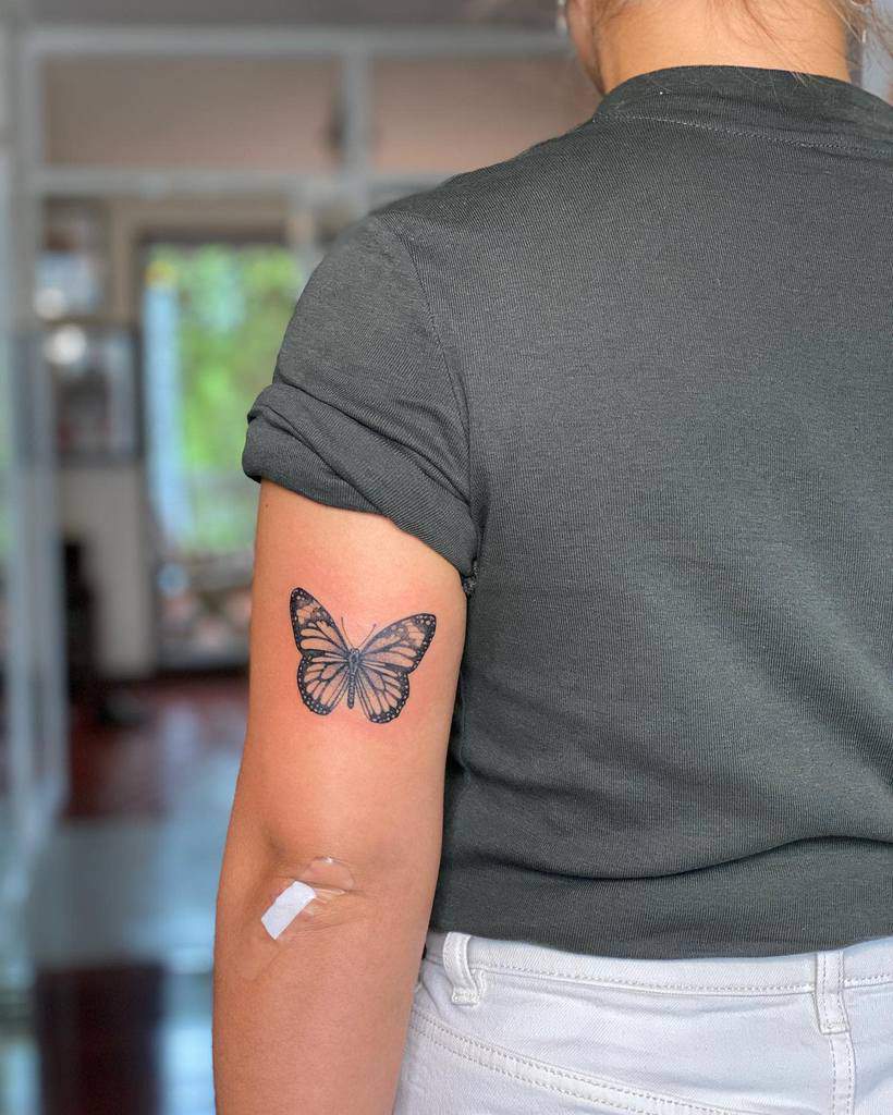 A woman with a monarch butterfly tattoo on her upper arm