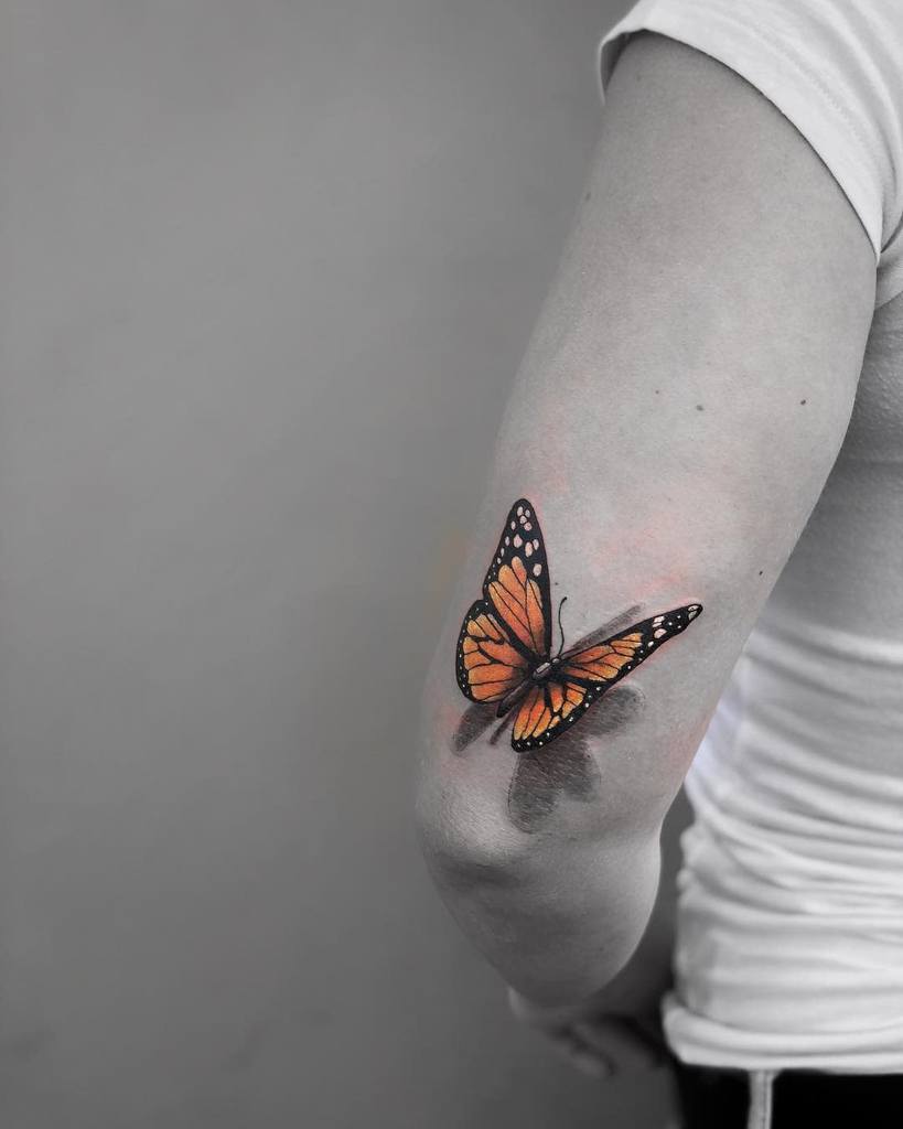 A monarch butterfly tattoo graces the person's arm