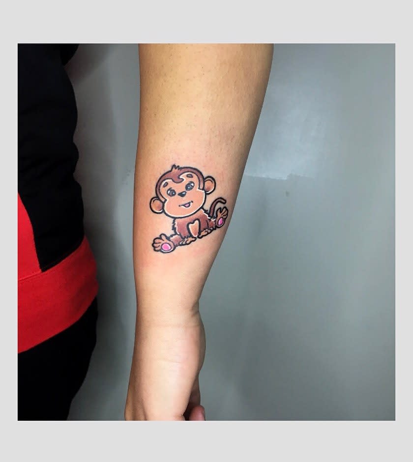 A colorful monkey tattoo on a forearm