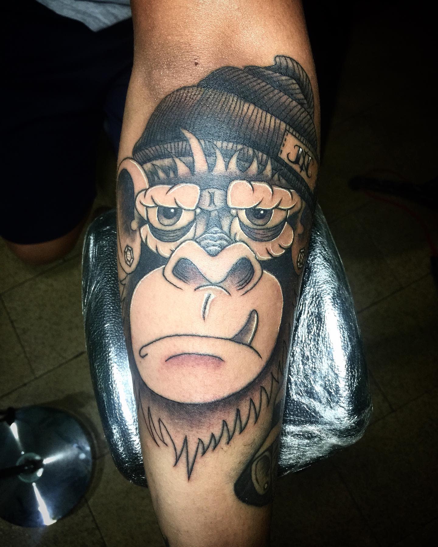 Forearm tattoo of a monkey wearing glasses and a beanie