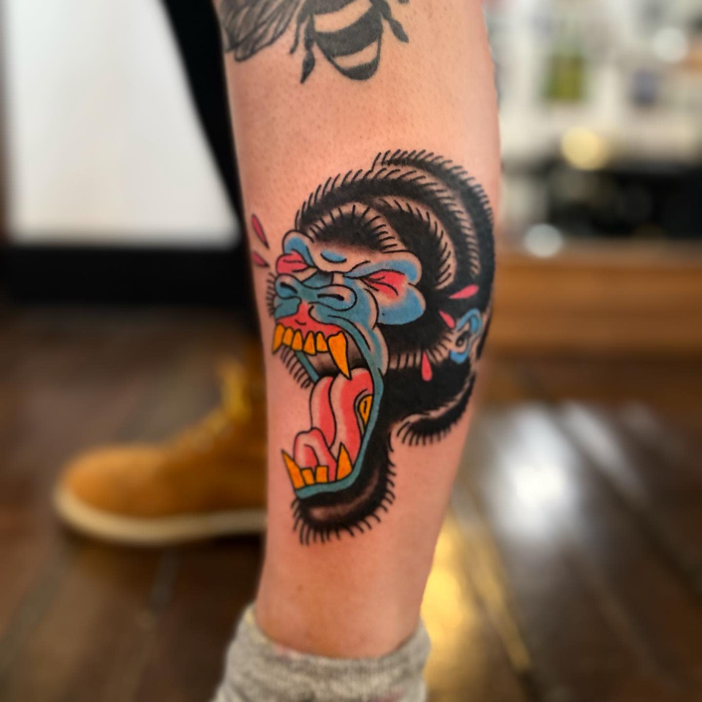 A colorful tattoo of a snarling gorilla head on a calf