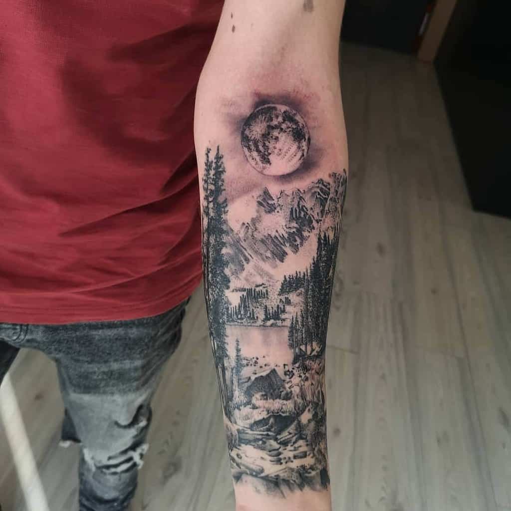 Tattoo of moon, mountains, and forest on a man's forearm