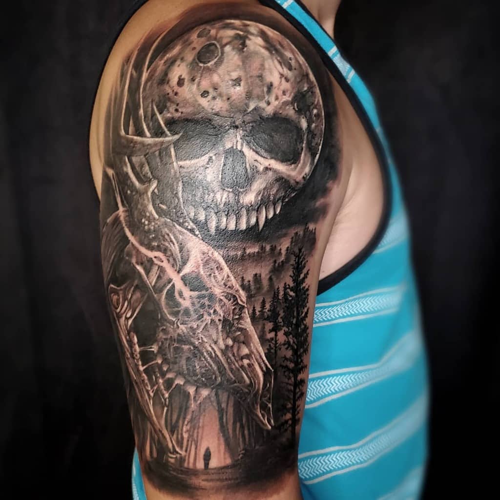 Arm tattoo with a skull moon, forest, and stag in grayscale detail