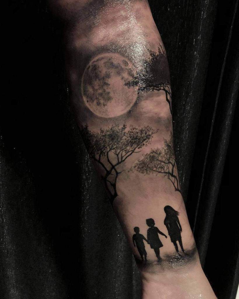 Tattoo of three silhouettes under trees with a full moon in the background