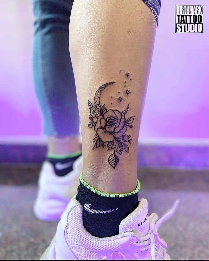 Tattoo of a crescent moon, glistening stars, and delicate roses on the back of a person's lower leg