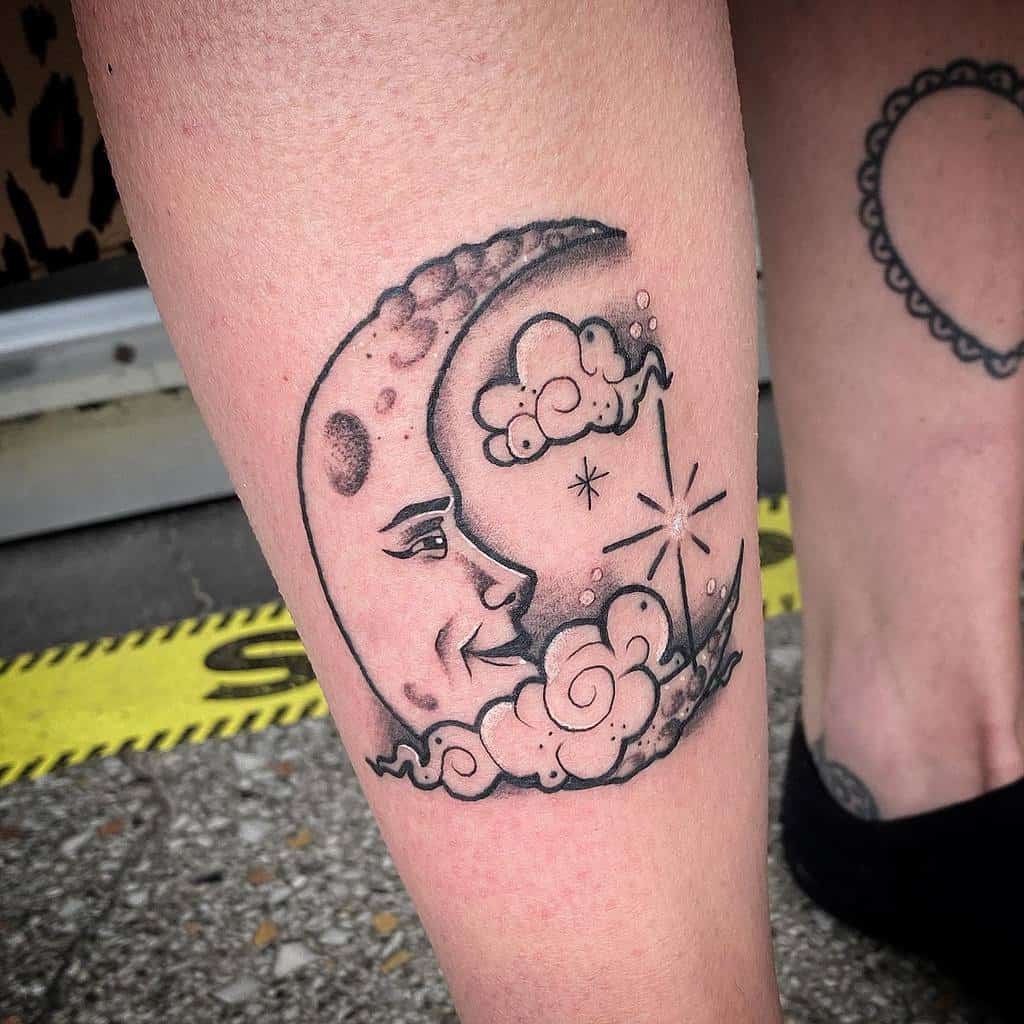 Tattoo of a crescent moon with a face, surrounded by twinkling stars and gentle clouds on a person's leg