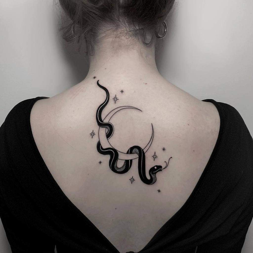 Black snake tattoo on upper back with stars and a crescent moon around it