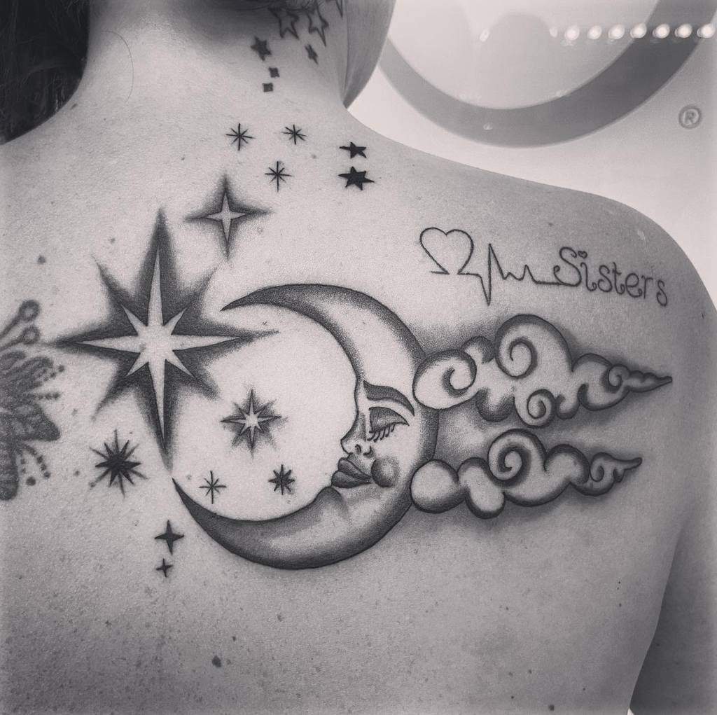Tattoo of moon and stars, clouds, heartbeat with "Sisters" text on person's upper back