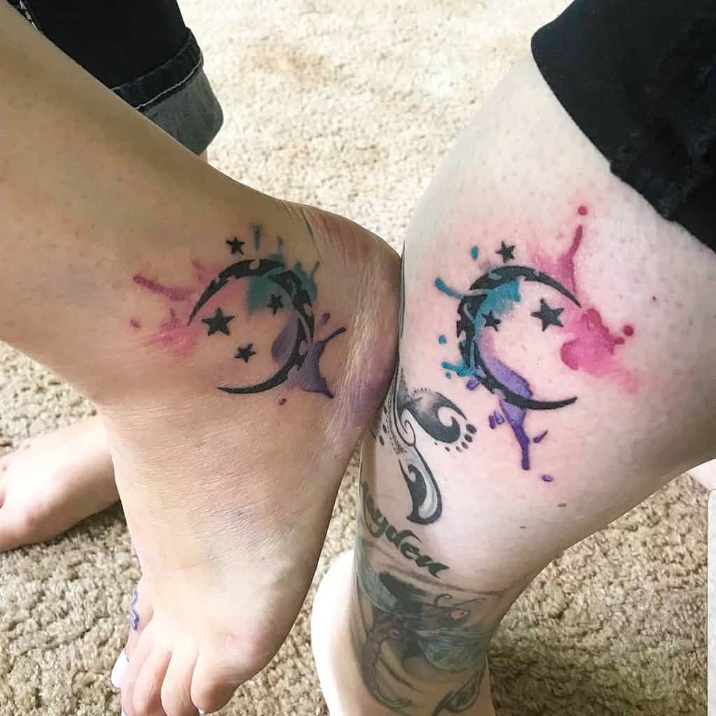 Matching moon and star tattoos on legs with vibrant watercolor splashes