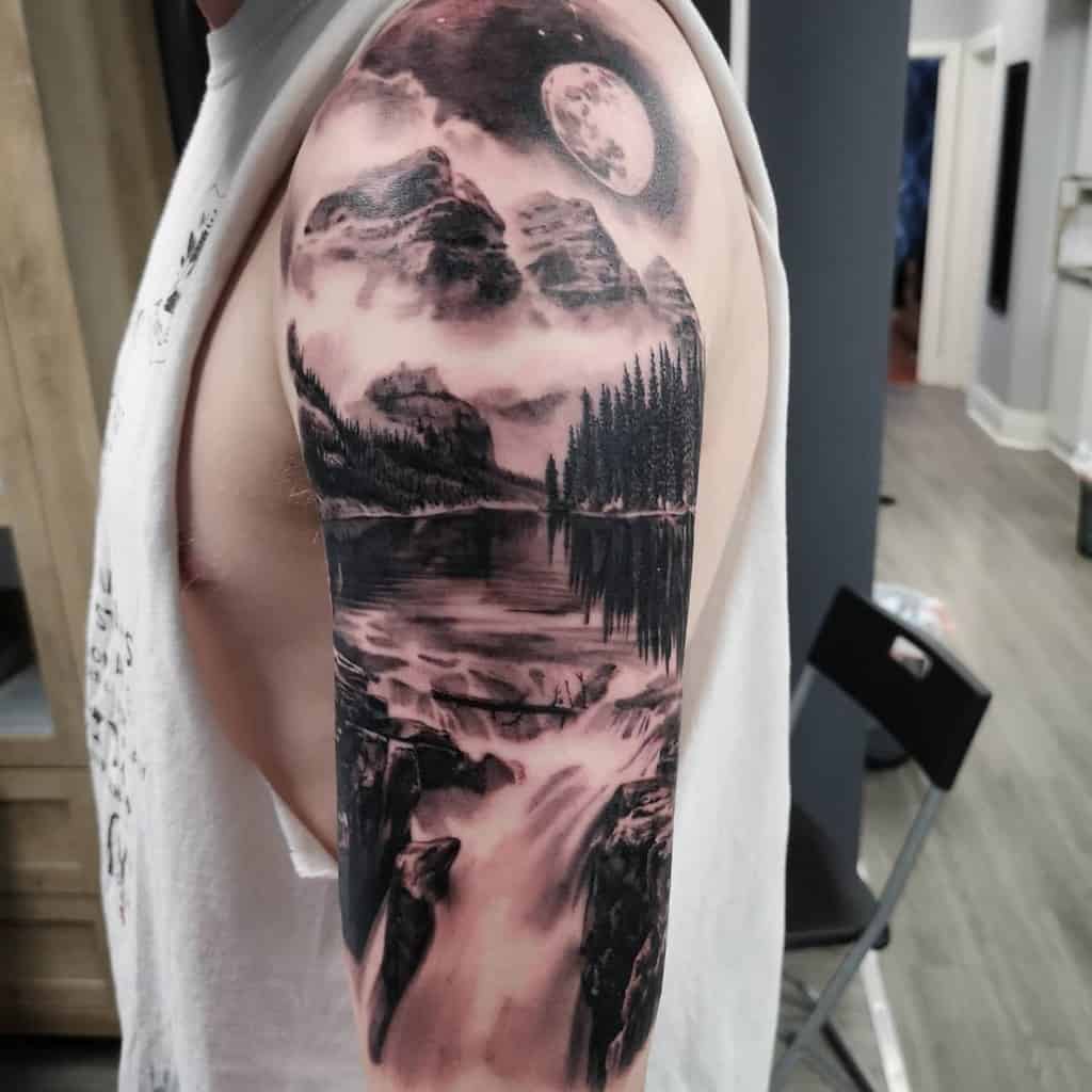 Arm tattoo with a mountain, moon, trees, and waterfall landscape