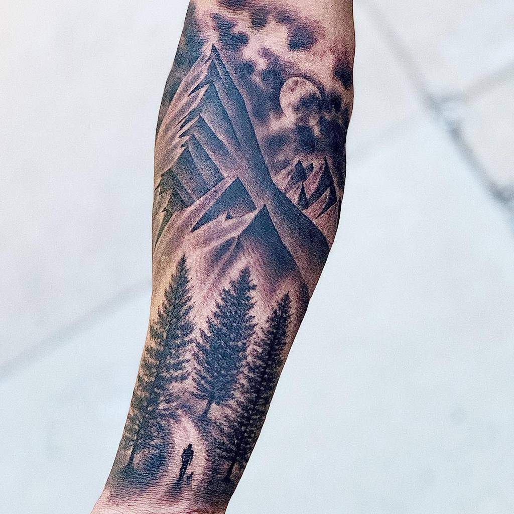 Forearm tattoo of a hiker in a forest with mountains and a moon in the background