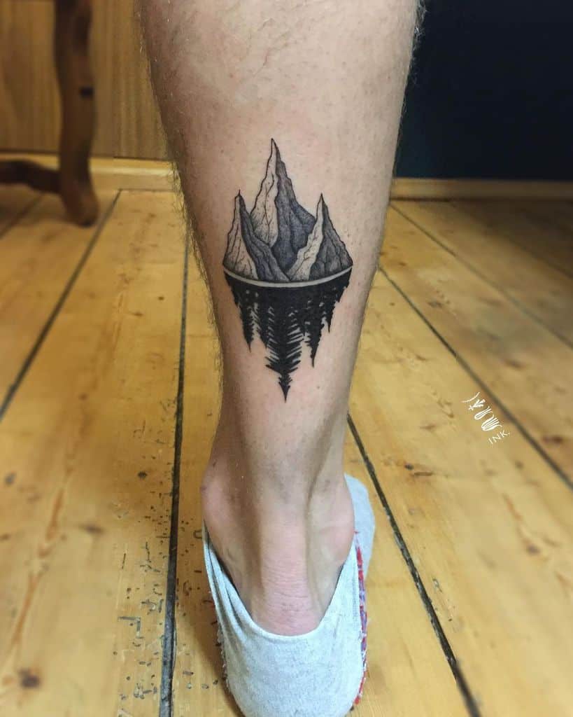 Leg tattoo featuring a geometric mountain range with a mirrored forest beneath it