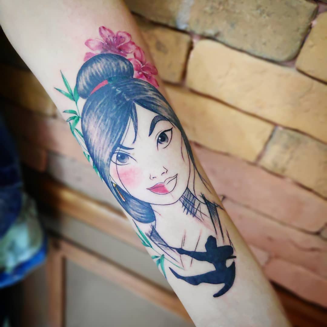 Forearm tattoo of Mulan with flowers in her hair and a silhouette of a warrior below