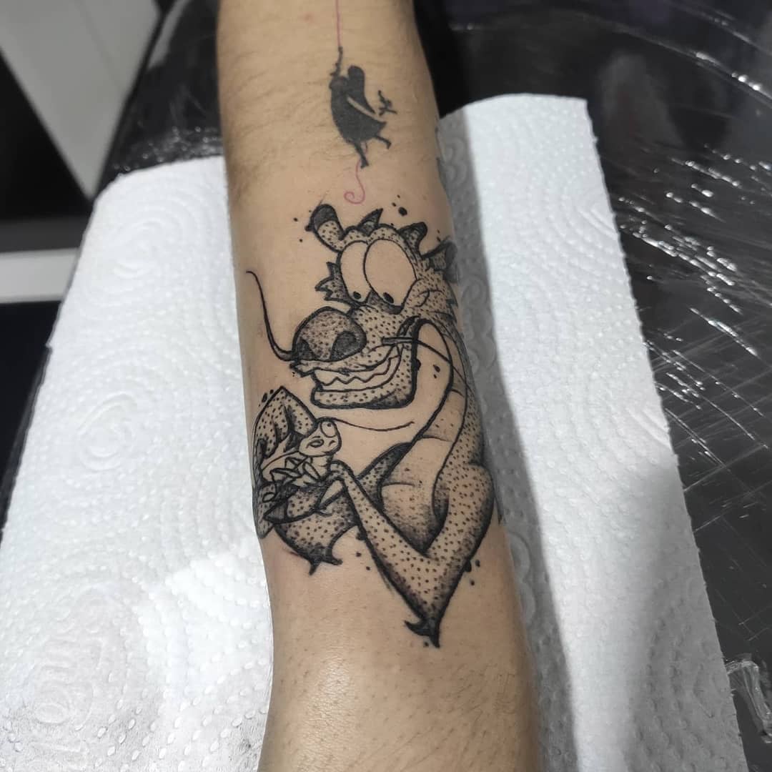 Tattoo of Mushu on an arm with Mulan small figure above it
