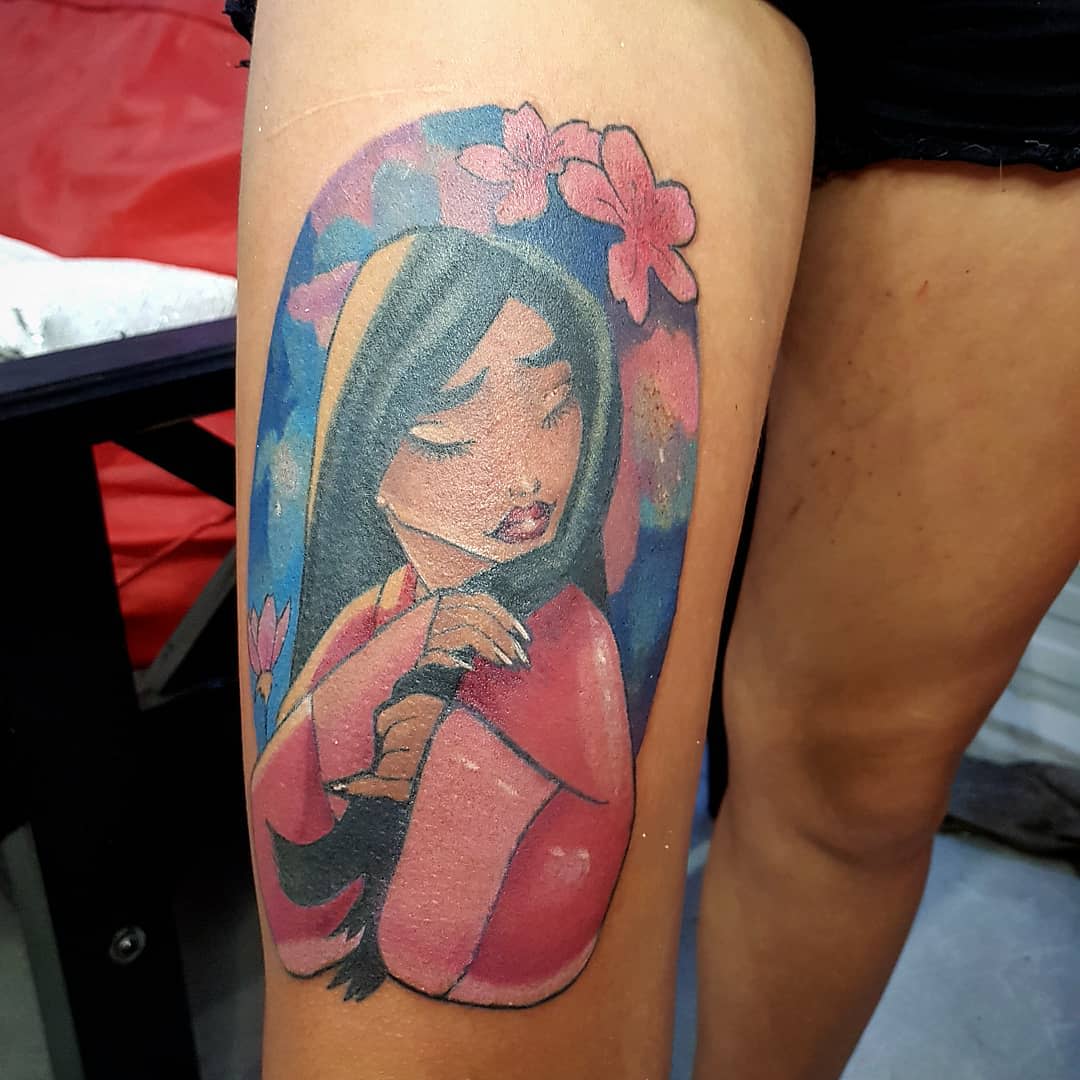 Close-up of a colorful tattoo showcasing Mulan with flowers on her arm