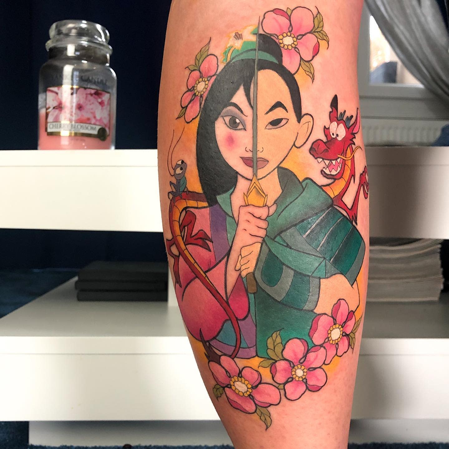 Leg tattoo featuring Mulan with cherry blossoms and a dragon in the background