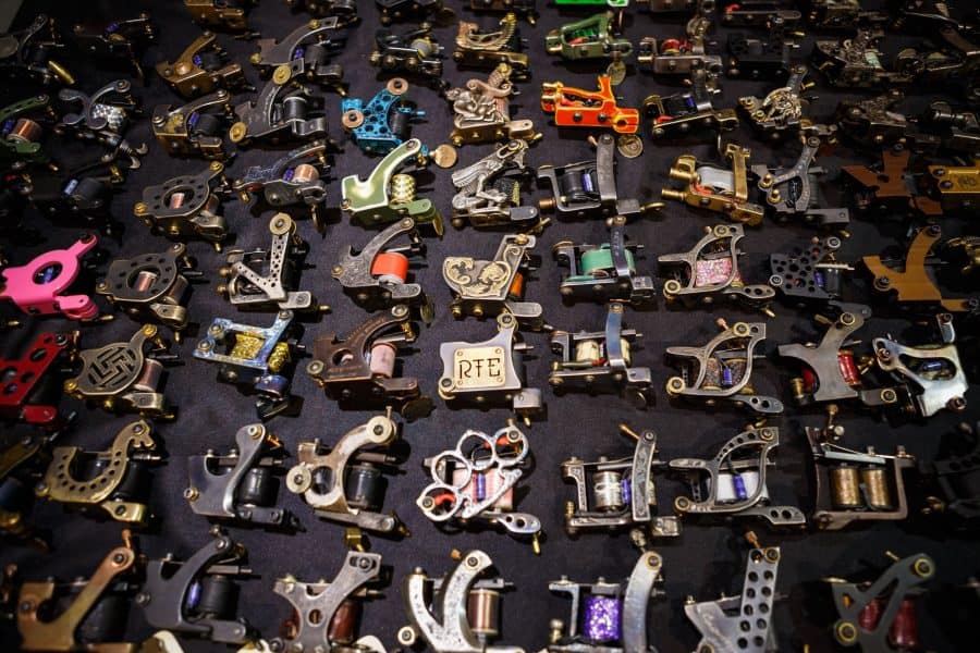 Assorted tattoo machines including single needle options displayed on a table showcasing various designs and colors
