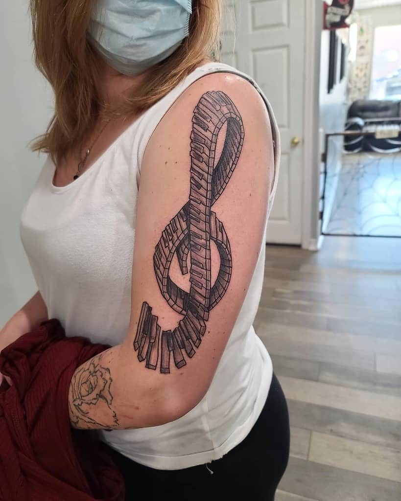 Woman with a musical note and piano keys tattoo on her arm