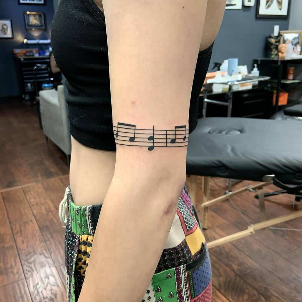 A woman with a musical note tattoo on their upper arm