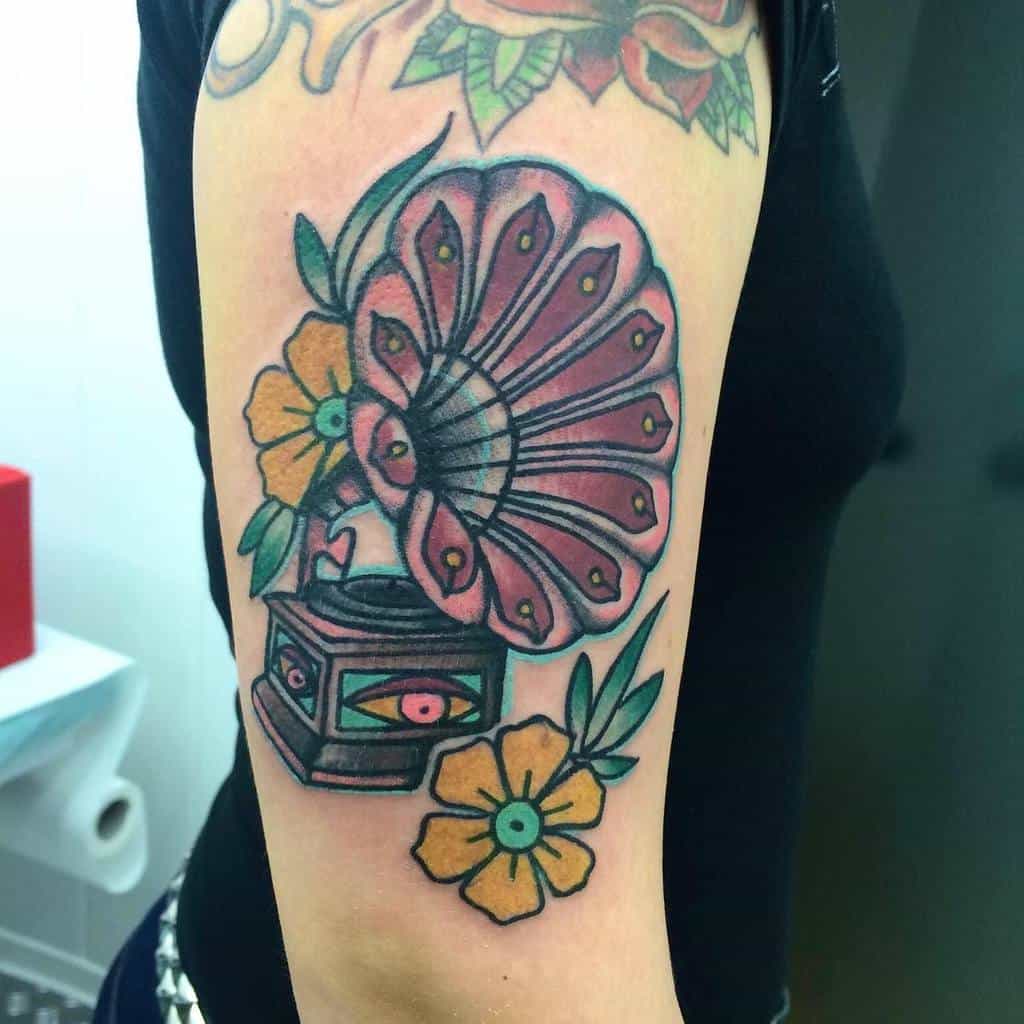 Tattoo of a colorful gramophone with flowers on a woman's upper arm