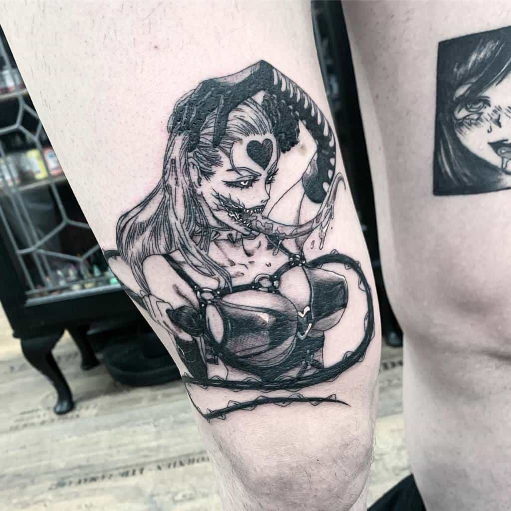 A black ink tattoo of a monstrous female character with sharp teeth and tentacle-like appendages, blending horror and anime-inspired elements