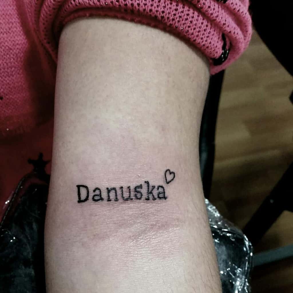Tattoo of the name "Danuska" with a small heart on a woman's arm