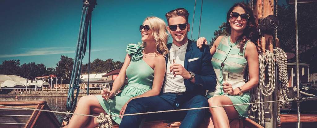 Stylish people drinking champagne sitting on a boat