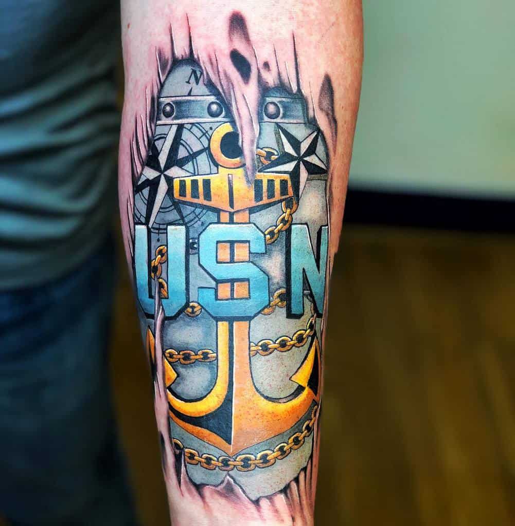 Tattoo of a navy anchor with "USN" on a forearm featuring chains and nautical symbols