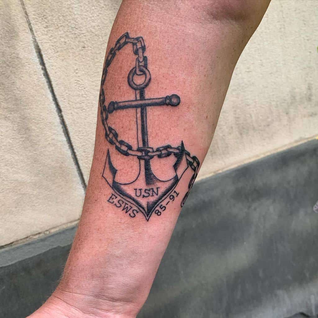 Navy anchor tattoo on forearm with chain and text "USN ESWS 85-91"