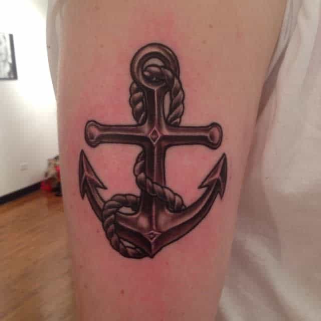 Tattoo of a black and gray navy anchor with rope wrapped around it on an upper arm