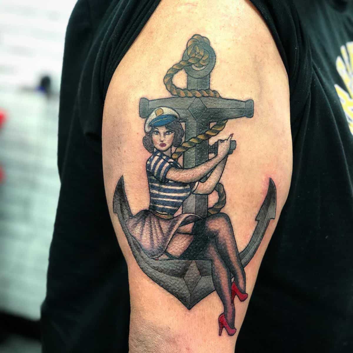 Tattoo of a sailor woman in a striped shirt and red heels holding an anchor on an upper arm