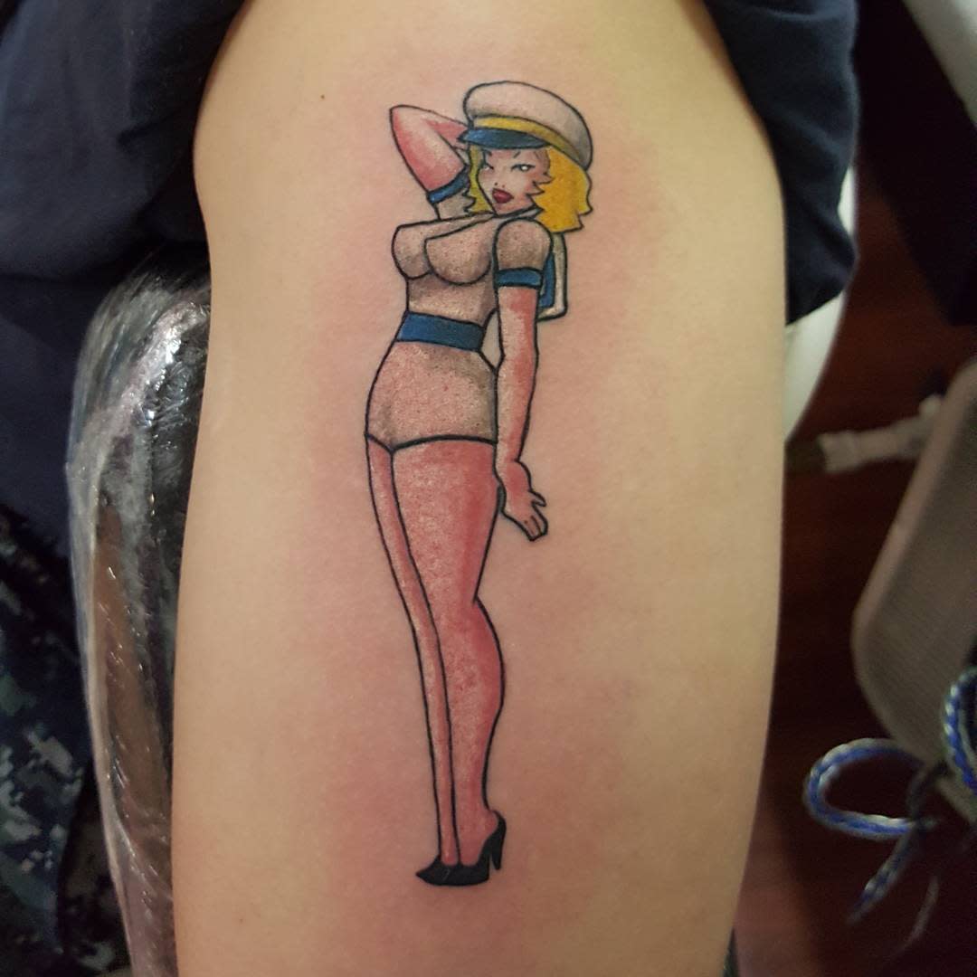 Tattoo of a blonde pin-up girl in a sailor outfit, posing with one arm behind her head