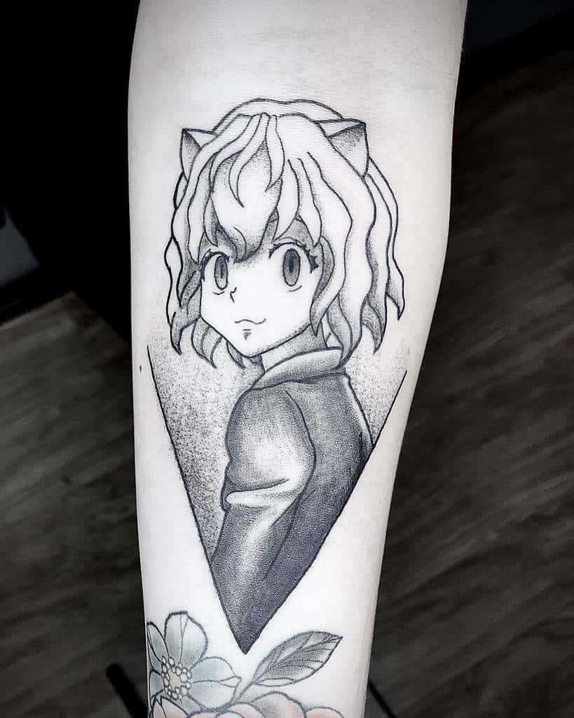 Black and gray tattoo of Neferpitou from Hunter X Hunter, with a cat ear motif, surrounded by a geometric shape, on a person's forearm