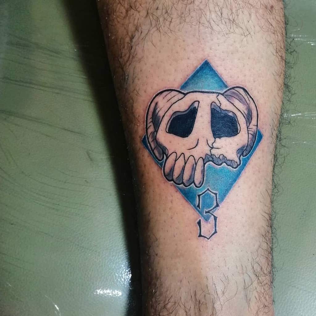 Colorful tattoo of Nelliel Tu Odelschwanck’s Hollow mask from Bleach, featuring a cracked ram skull design with a blue diamond background and the number 3