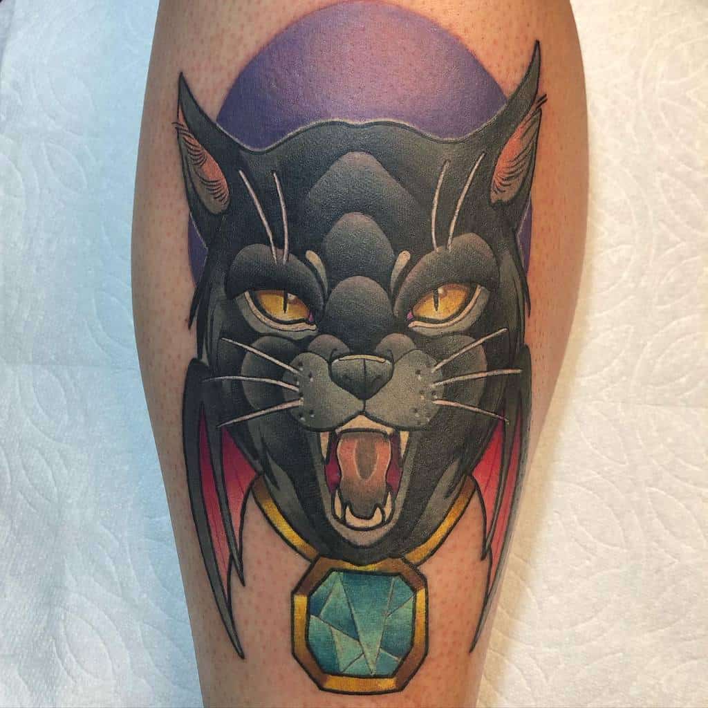 A tattoo of a fierce black panther with a blue pendant on a person's skin, embodying the strength and agility of a wild cat