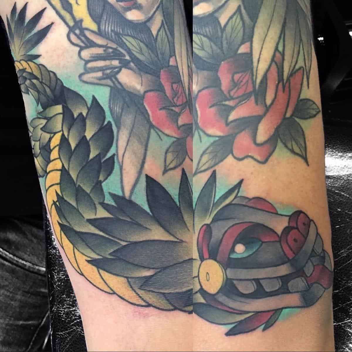 Neo-traditional Quetzalcoatl tattoo featuring bold colors and detailed feathered serpent head with floral elements