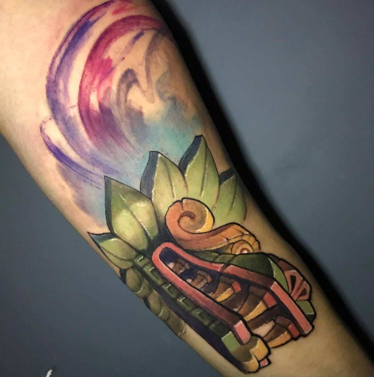 Colorful neo-traditional Quetzalcoatl tattoo with vibrant green, red, and purple tones, featuring the serpent's head and swirling background
