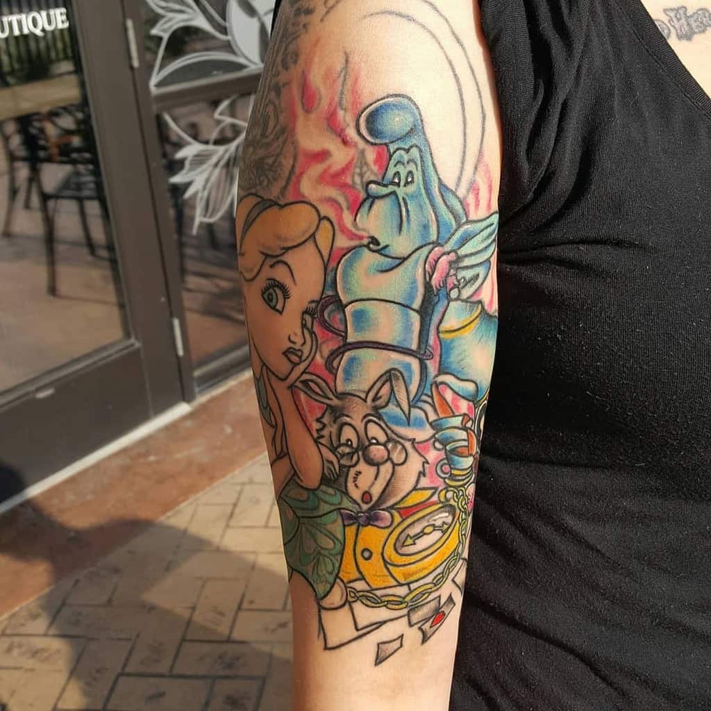 Colorful tattoo featuring characters from Alice in Wonderland, including Alice, the Caterpillar, and the White Rabbit, surrounded by vibrant tea party details, pocket watch and heart cards