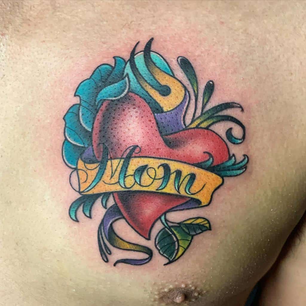 Chest heart tattoo with "Mom" banner, surrounded by vibrant flowers and lush leaves in various colors