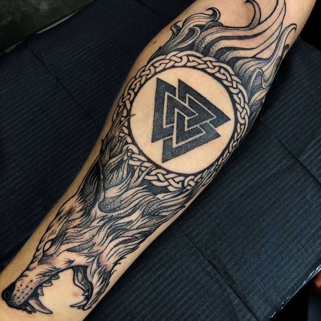 A tattoo featuring a wolf's head with flowing lines, encircling the Valknut symbol surrounded by intricate knotwork
