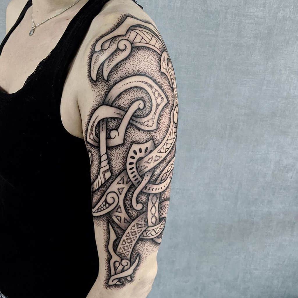 A Nordic shoulder tattoo featuring intricate knotwork designs and stylized animal figures, created with detailed dotwork shading throughout
