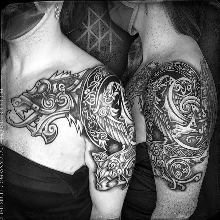 A Nordic shoulder tattoo featuring a stylized dragon and intricate knotwork, with bold shading and detailed patterns emphasizing Viking mythology