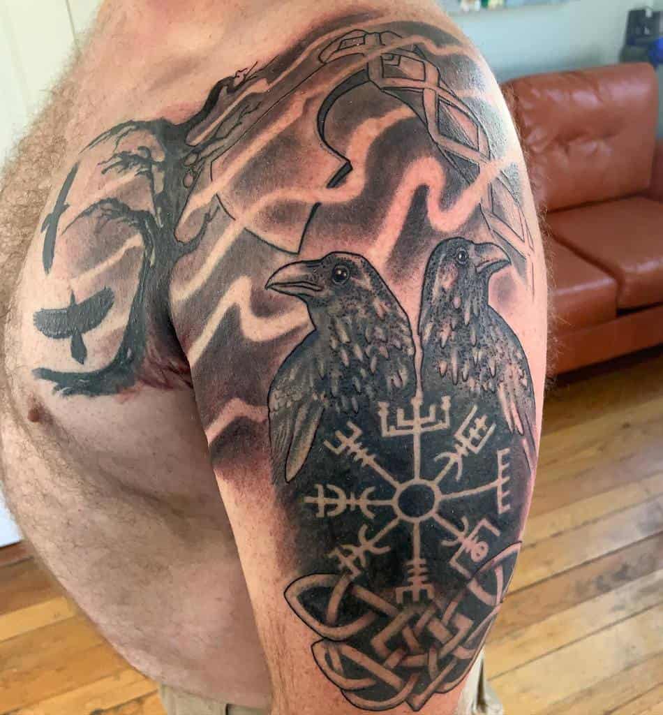 A Nordic shoulder tattoo featuring two ravens, the Vegvisir symbol, and intricate knotwork, with additional shaded elements like a tree and winding branches in the background