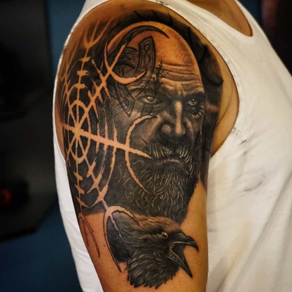 Nordic shoulder tattoo featuring a detailed portrait with Viking elements, knotwork, a raven, and runes