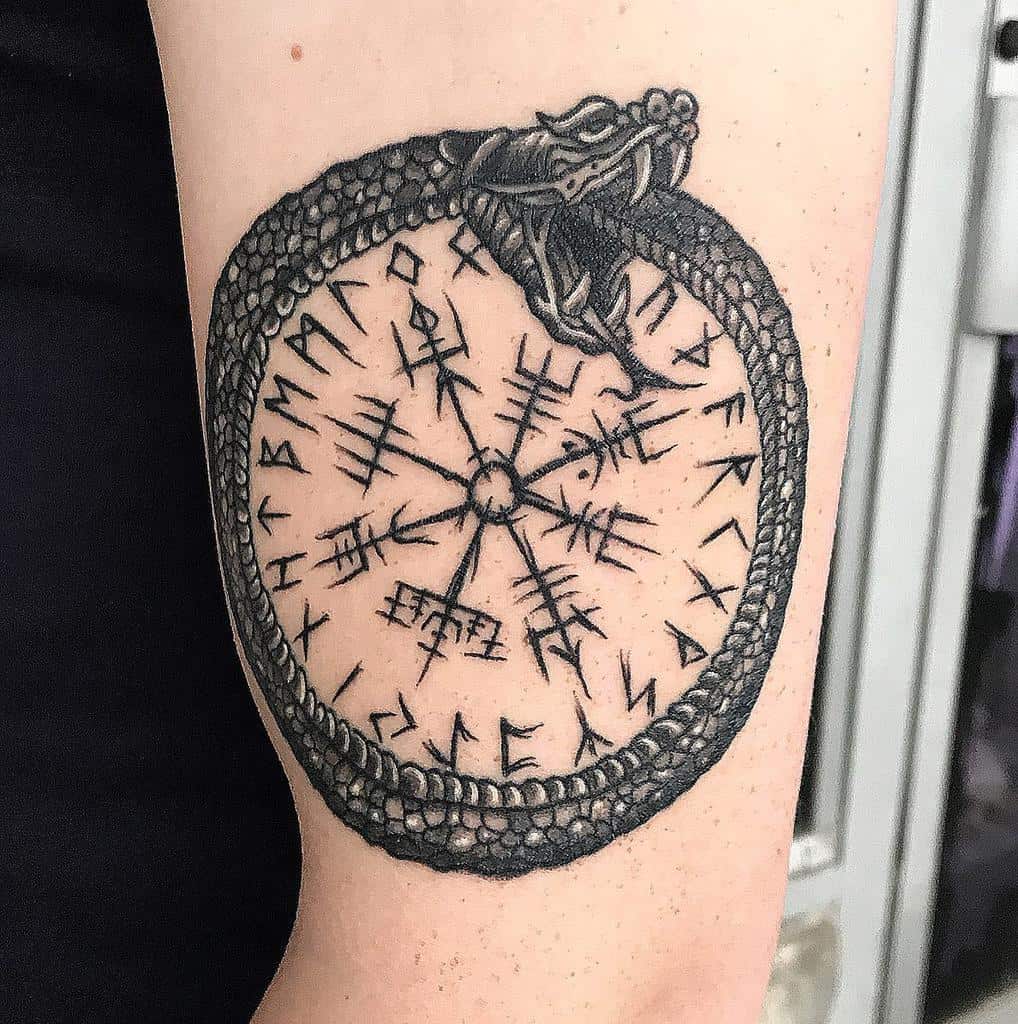 Tattoo of a Norse rune circle encircled by a dragon, symbolizing Ouroboros, on an upper arm