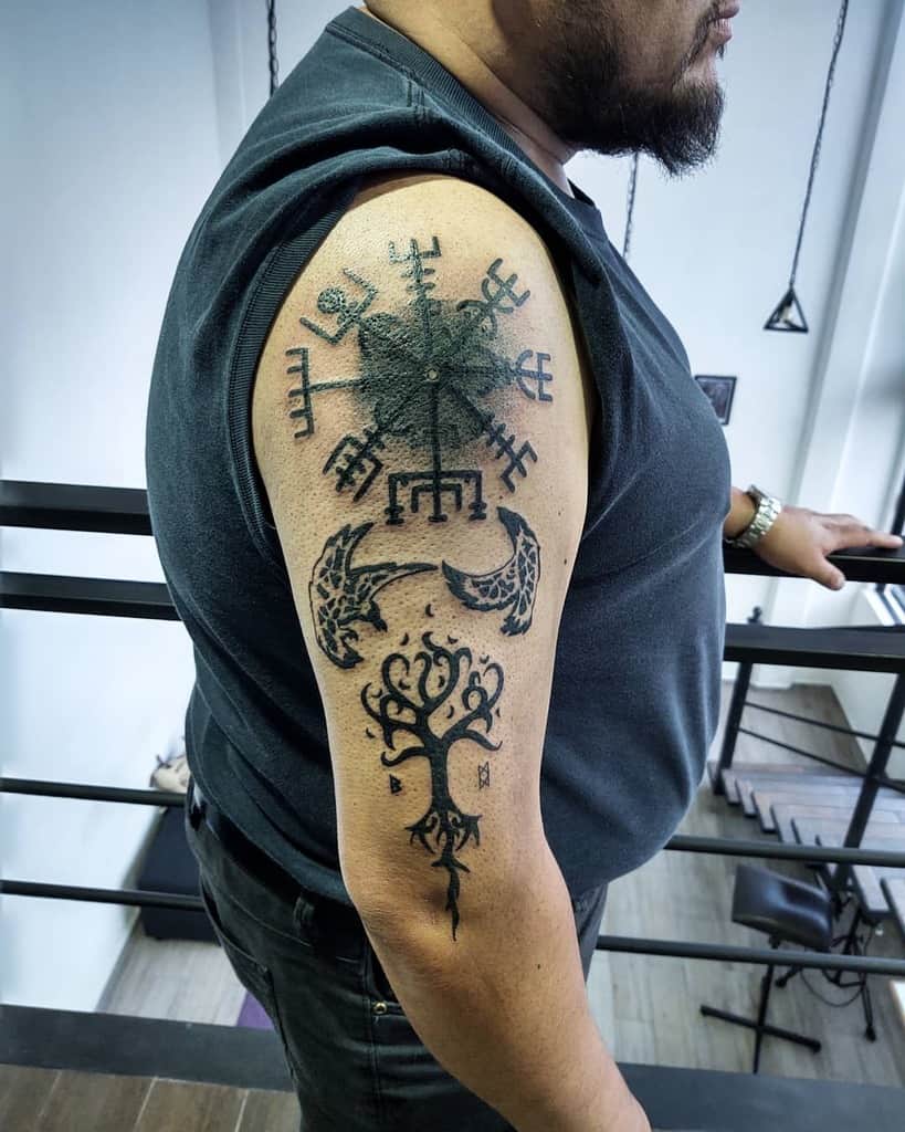 Nordic-themed upper arm tattoo featuring a Vegvisir, Yggdrasil, and a stylized moon, symbolizing guidance, life, and cycles