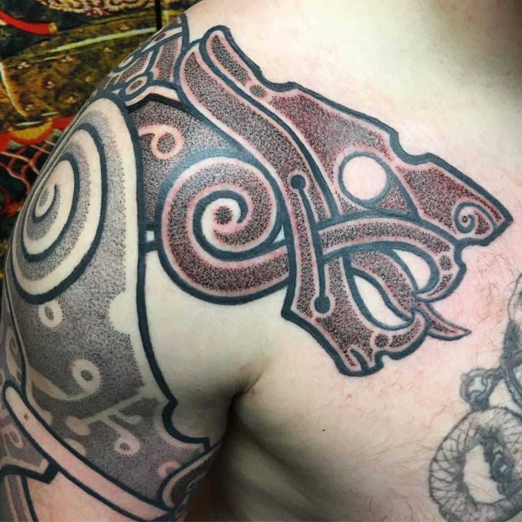 A shoulder tattoo featuring a majestic bear surrounded by intricate spirals, geometric shapes, and dot shading in striking black and red tones
