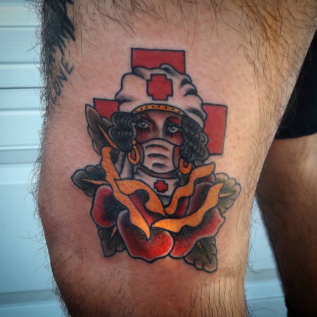 Tattoo of a nurse with a mask and cap, framed by a red cross and rose petals