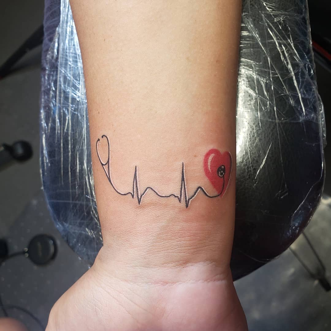 A wrist tattoo of a heartbeat line ending in a red heart